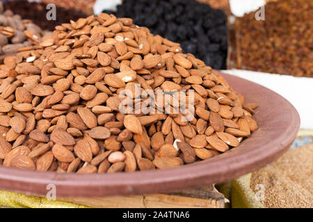 Un mucchio di mandorle ben presentato su una piastra con altra frutta secca in background in un mercato tradizionale di stand nei souks, Marocco Foto Stock