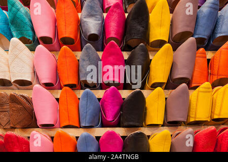 Scarpe colorate in un negozio di mercato in un souk in Marocco. Tali tipi di pantofole sono chiamati babouches. Foto Stock