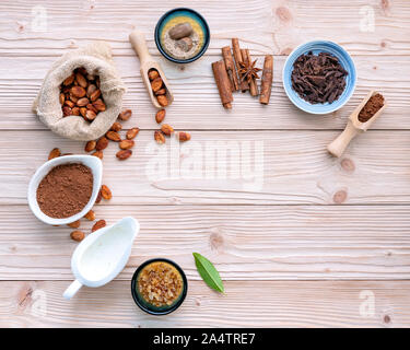 Cacao in polvere e chicchi di cacao su sfondo di legno. Cioccolato fondente pezzi frantumato e erbe aromatiche . Foto Stock