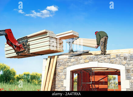 La posa di elementi isolanti sul tetto di una casa in costruzione. Foto Stock