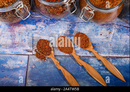 Spezie fragranti in cucchiai di legno e barattoli di vetro sul tavolo Foto Stock