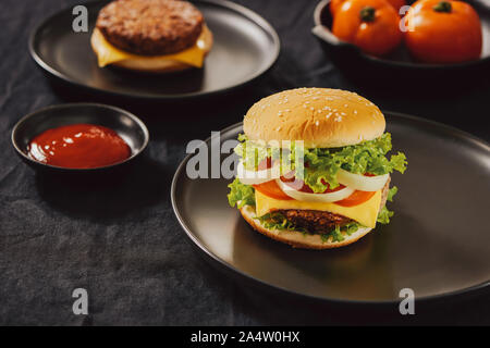 Hamburger di manzo hamburger di carne e verdure fresche su sfondo scuro. Gustosi piatti fast food Foto Stock