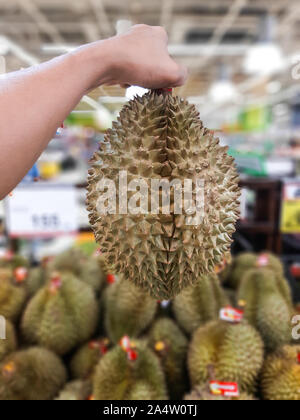 Mano sinistra tenendo Durian Durian, in vendita nel supermercato, re di frutta. Foto Stock