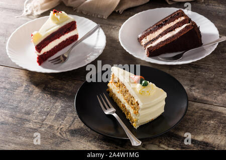 Assortimento di dolci fette di torta. Il cioccolato, la carota e il velluto fette di torta sul tavolo di legno Foto Stock