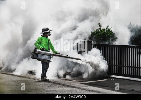 Uomo che utilizza fogger macchina a controllo da pericolose zanzare Foto Stock