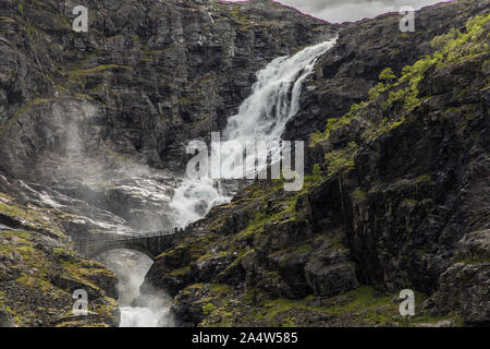 Norwegian mountain road. Trollstigen. Cascata Stigfossen. Il sole di mezzanotte oltre la Norvegia paesaggio turistico Valle. Foto Stock