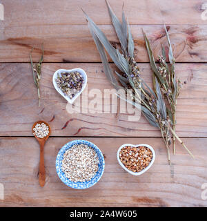 Cibo sano, organico insieme i grani di riso Miglio nella ciotola ,miglio bianco e il miglio di cob contro di legno rustico sfondo. Foto Stock