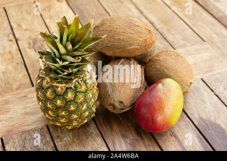 La foto di un ananas, noci di cocco e mango sul tavolo di legno Foto Stock