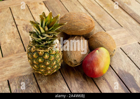 La foto di un ananas, noci di cocco e mango sul tavolo di legno Foto Stock