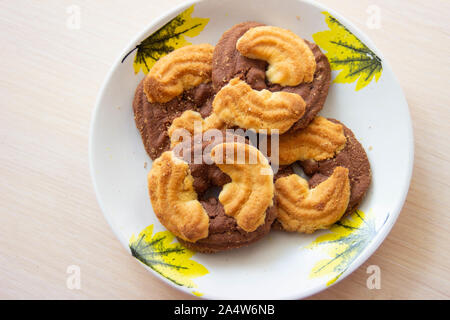 La foto di una pila di biscotti con scaglie di cioccolato e biscotti shortcake sulla piastra. Cookie nazionale giorno sullo sfondo Foto Stock