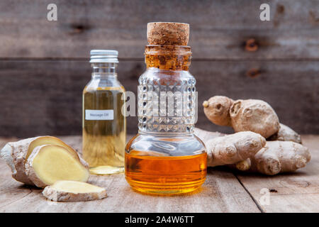 Medicina alternativa e natura terme ingredienti - radice di zenzero e lo zenzero olio essenziale impostato sul vecchio tavolo in legno. Foto Stock