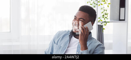Allegro americano africano dipendente avente telefonata piacevole sul luogo di lavoro Foto Stock