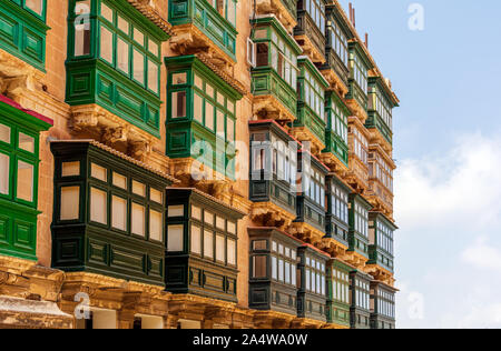 Casa residenziale con facciata tradizionale maltese in legno verde racchiuso balconi a La Valletta, Malta, nella luce del sole serale. Foto Stock