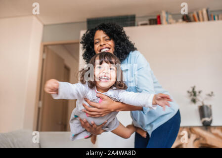 Madre scherzosamente oscillare la figlioletta nell'aria Foto Stock