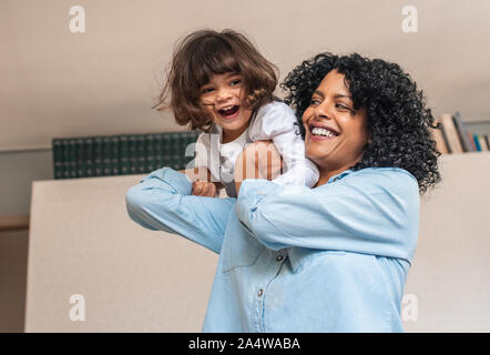 Ridendo mom e carino piccola figlia gioca in casa Foto Stock