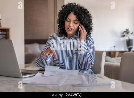 Imprenditore femmina parlando sul suo cellulare mentre si lavora a casa Foto Stock