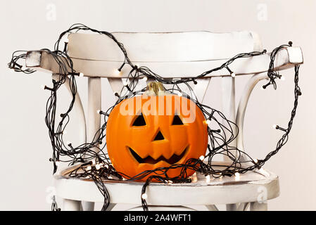 Zucca di Halloween di testa con taglio del volto e la ghirlanda sulla sedia Foto Stock