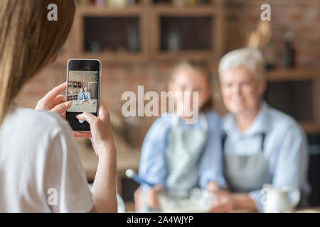 Donna prendendo foto sullo smartphone in cucina Foto Stock