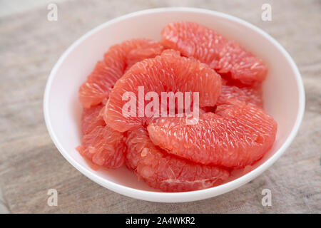 Pompelmo rosso fette in una ciotola bianco su tela, vista laterale. Close-up. Foto Stock