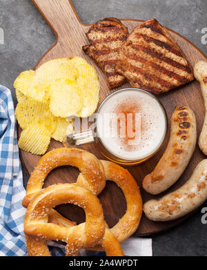 Oktoberfest set. Salatini, salsicce, carne e lager boccale di birra su sfondo di pietra. Vista superiore Foto Stock