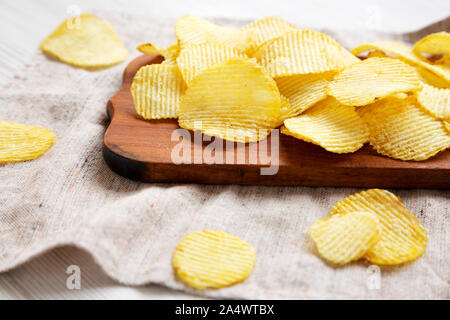 Ondulata salata potato chips su un rustico di legno, vista laterale. Primo piano. Foto Stock