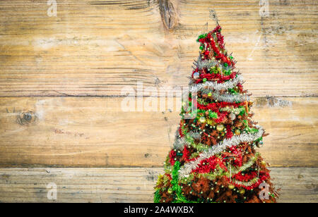 Vista laterale del vecchio albero di Natale con decorazioni su sfondo di legno. Biglietto di auguri o poster sfondo. Foto Stock