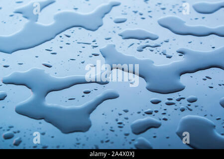 Acqua su uno sfondo blu. Gocce di blu di acqua sul vetro. Macchie di acqua. Foto Stock