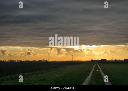 Una bassa inverno il sole splende al di sotto di uno strato di nubi causando un drammatico sky Foto Stock