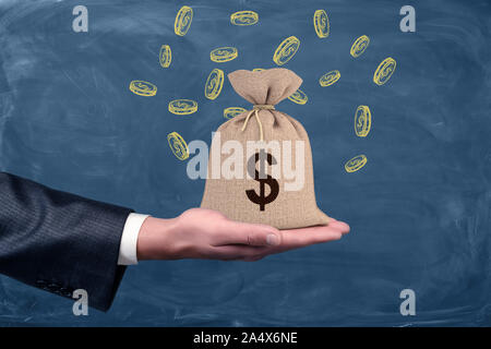 Chiuso un sacco di denaro in piedi su imprenditore il palmo sulla lavagna sfondo. Foto Stock