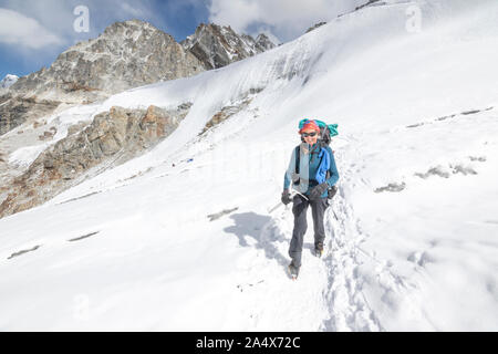 Una donna alpinista con ghiaccio ax sorrisi mentre attraversano un ghiacciaio Foto Stock