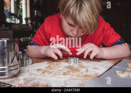 Vista frontale del ragazzo taglio gingerbread da impasti Foto Stock