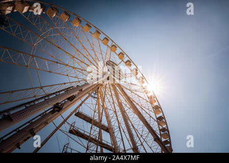 Ampia angolazione del grande ruota panoramica Ferris contro il cielo blu con sunburst Foto Stock