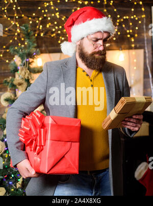 Uomo Barbuto hipster usura santa hat tenere mazzetto di lettere e confezione regalo. Post per babbo natale. Lettera a Babbo Natale. Uomo Barbuto con occhiali lettura posta per santa. Spirito di miracolo d'inverno. Foto Stock