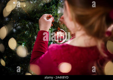 Immagine festosa di ragazza decorare albero di Natale la riflessione in pallina Foto Stock