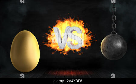 3D rendering di un calcestruzzo grandi lettere VS sul fuoco stand tra una grande Golden Egg e un nero ferro Wrecking Ball. Foto Stock