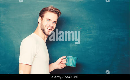 Uomo bello gustare caffè caldo. Il caffè di tossicodipendenti. Bevanda stimolante. Dose di caffeina. Insegnante bere il caffè lavagna sfondo. Buona mattina. Il protocollo SIP ricaricare corpo e mente. Carica di energia per tutta la giornata. Foto Stock