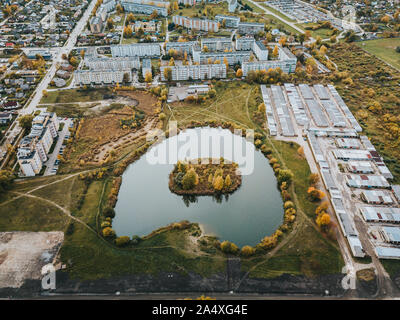 Vista aerea di un piccolo laghetto con isola circondata dai sovietici fatto isolato di appartamenti case in città Jelgava Lettonia Foto Stock