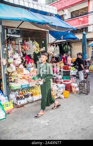 Mae Sot, Tailandia - 3 Febbraio 2019: un giovane musulmano uomo cammina davanti a un negozio di alimentari sul mercato. Il mercato è un fatto quotidiano. Foto Stock