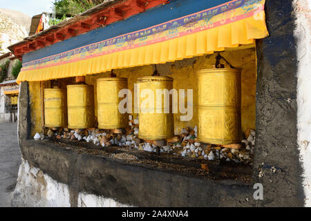 Golden ruote della preghiera al monastero di Drepung attendere un adoratore di Bhuddhism tibetano a girare una preghiera per l'universo. Foto Stock