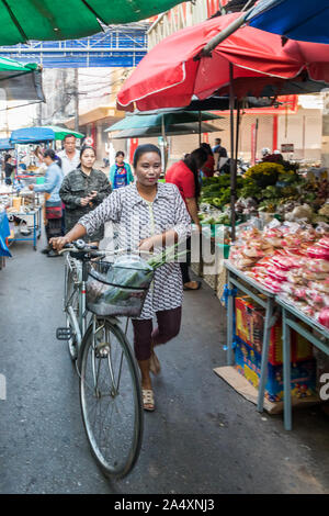 Mae Sot, Tailandia - 3 Febbraio 2019: Donna bicicletta spinta attraverso il mercato. Il mercato è un evento quotidiano al mattino. Foto Stock