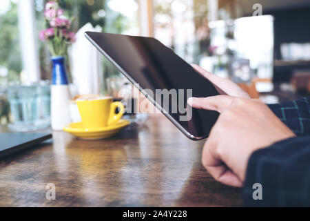 Primo piano immagine di una mano rivolto , toccare e utilizzo di tablet pc con blur sullo sfondo in cafe Foto Stock
