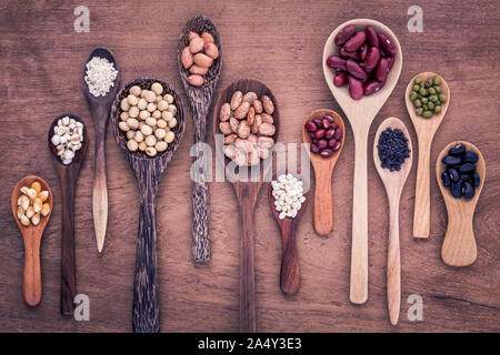 Assortimento di fagioli e lenticchie in cucchiaio di legno su legno di teak dello sfondo. Mung bean, arachide, soia, fagioli fagioli , fagiolo nero ,sesame, mais ,ri Foto Stock