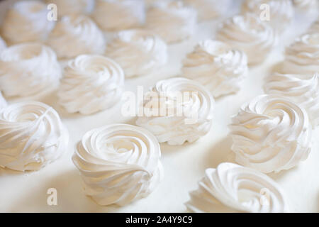 Preparazione di un bianco torta di meringa Pavlova. Meringa volute su sfondo bianco Foto Stock