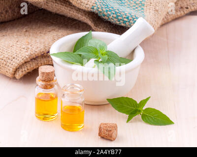 Medicina alternativa basilico limone olio naturale terme ingredienti per aroma aromaterapia con mortaio su sfondo di legno. Foto Stock