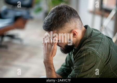 Uomo Barbuto indossando maglietta controllati aventi un forte mal di testa Foto Stock