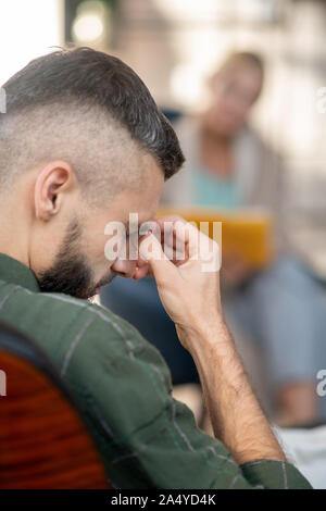 Man aventi mal di testa mentre ascolto psicanalista Foto Stock