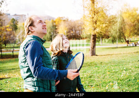 Un padre e figlio di età scolare stanno parlando con badminton racchetta Foto Stock