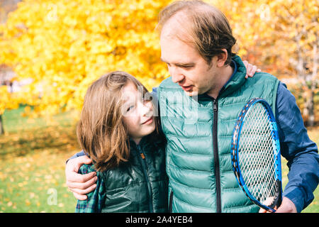 Un padre e figlio di età scolare stanno parlando con badminton racchetta Foto Stock