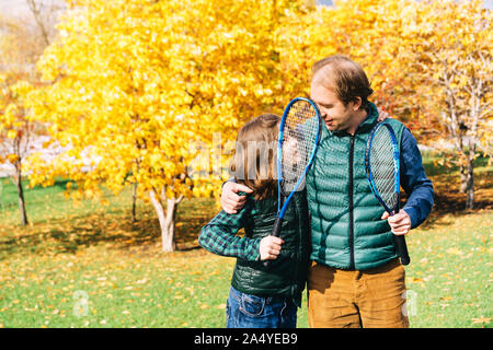 Un padre e figlio di età scolare stanno parlando con badminton racchetta Foto Stock