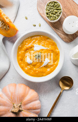 In autunno la zucca e la carota minestra di crema sulla pietra grigia sullo sfondo. Vista da sopra. Colpo verticale. Foto Stock